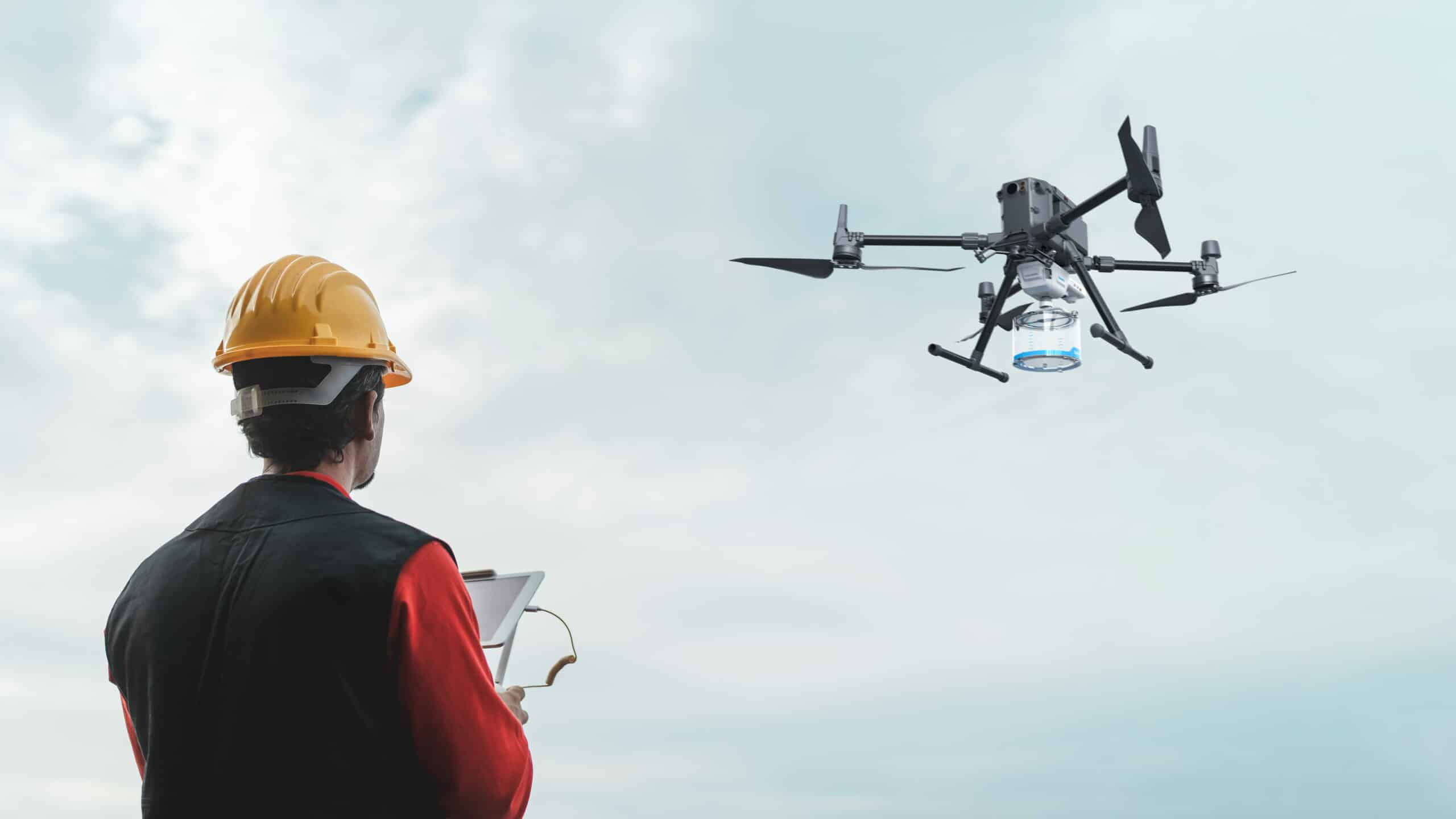 Engineer in hard hat operating commercial drone outdoors, AlphaGeo UAV survey equipment