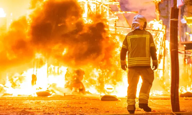 Firefighter in safety gear at substation fire with smoke and flames, AlphaGeo survey equipment context