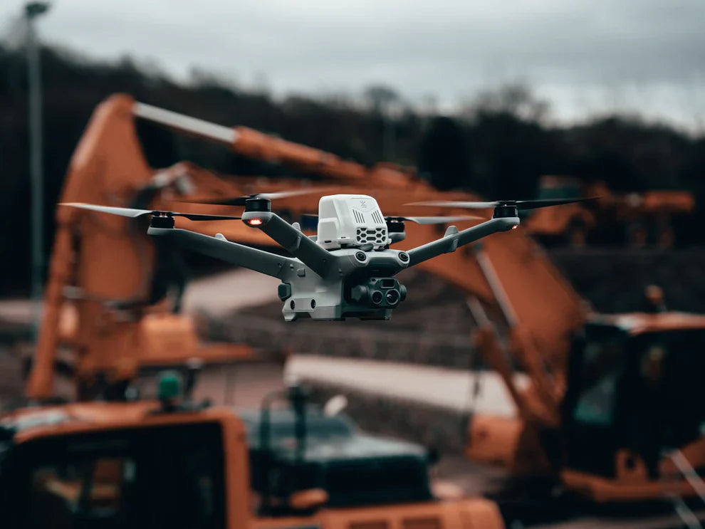 Commercial drone flying at a construction site with excavators, AlphaGeo survey equipment