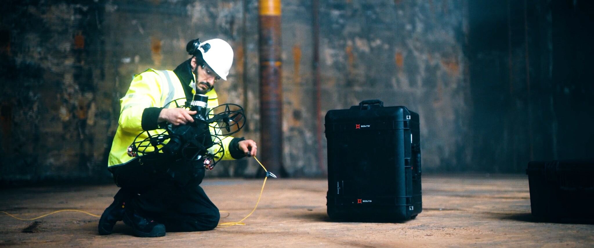 Engineer in safety gear preparing industrial survey drone beside hard case, AlphaGeo robotics equipment