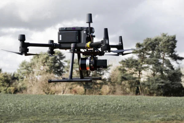 Commercial drone with camera flying outdoors over a field, AlphaGeo survey equipment UK